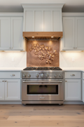 48 inch dogwood blossom copper backsplash panel in transitional kitchen with gray cabinets